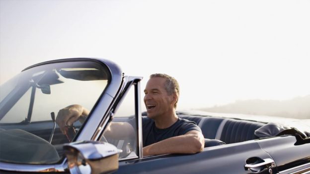 A mature happy man in a convertible car.