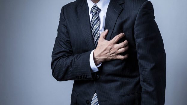 Man in suit holding his side in pain experiencing symptoms of stress