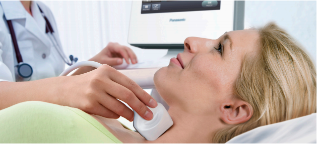 Woman in green shirt looking at ceiling while getting an ultrasound of her carotid taken. 