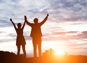 Silhouette of couple cheering in morning sunset