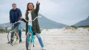 Couple riding bikes on the beach exercising for optimal health 