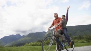 Couple on a bike smiling and laughing and having fun with strong healthy energy levels