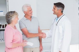 Dr. greeting older couple, having a great and informative patient experience.