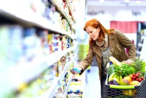 Mature red-headed woman in brown jacket shopping for nutritionally dense foods to improve her mental acuity