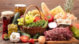 image of an abundance of food including meat, garlic, bread, raw veggies, fruit, olives, a pineapple, etc to eat while intermittent fasting 