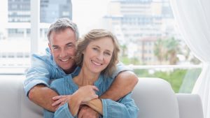 happy couple sitting on couch at home, hormone replacement therapy can increase sex drive due to optimal testosterone levels
