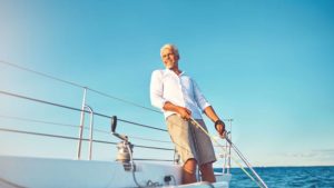 Older man smiling on sailboat in water proving the difference between biological age versus chronological age