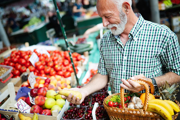 mature man shopping for in season fruits and vegetables at farmers market for non-contaminated food