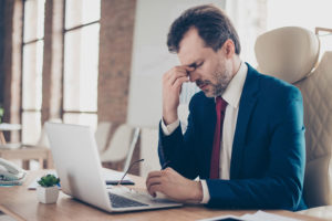 Mature male businessman wearing suit holding the bridge of his nose with closed eyes, Tired businessman suffering from cognitive/mental fatigue caused by hypothyroidism