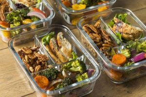 Chicken, pecans, and mixed vegetables in glass container for healthy meal prepping