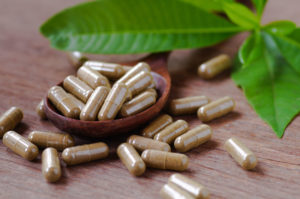 Supplement pills in wooden spoon again grain background, herbal supplement in pill and capsule on wood table with green leaves, methylation supplements