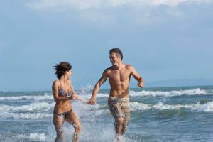 Man and woman running in ocean in good health & wellness 