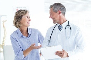Mature female patients smiling at male physician while looking over results with no symptoms of heart disease