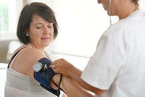 Mature woman having blood pressure checked by nurse in doctor’s office for metabolic syndrome