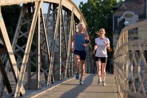 Man and woman jogging over bridge having improved energy gone through Cenegenics program and not only a low-t center