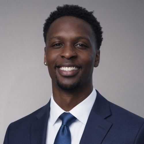 A man wearing a dark blue suit and a blue tie smiles directly at the camera.